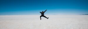 Man leaping into the air against a blue sky background.
