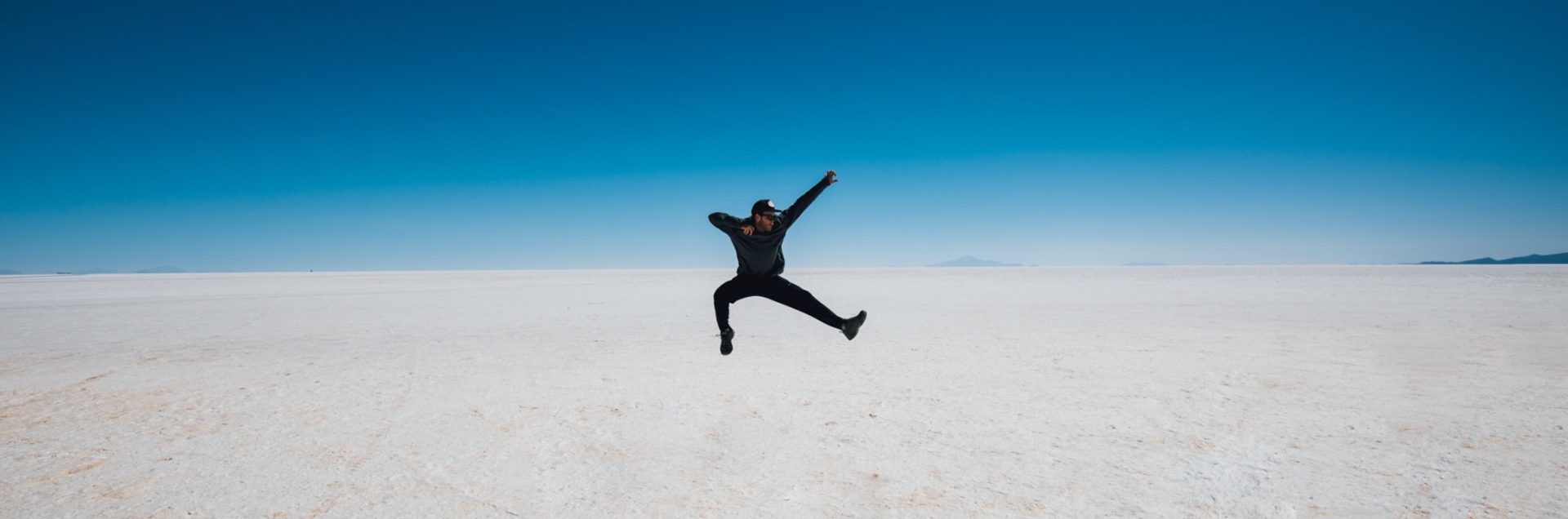 Man leaping into the air against a blue sky background.