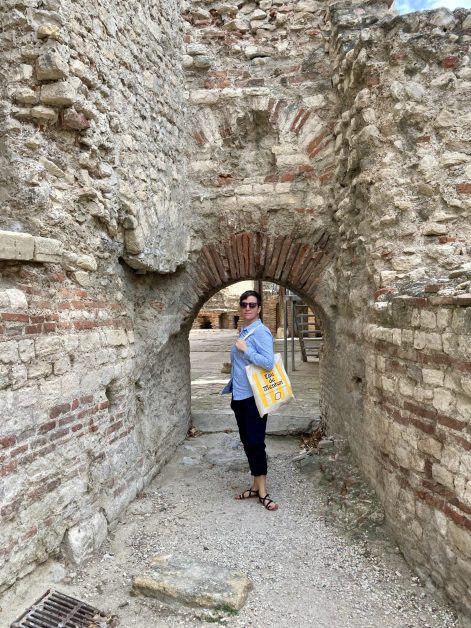 Lindsey standing in an arched doorway, carrying a tote bag.