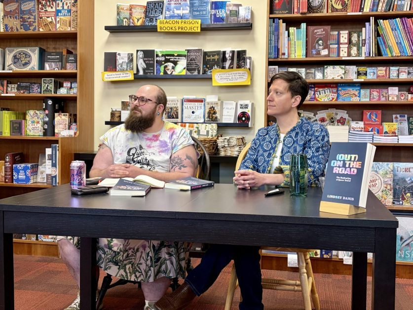 Author and conversation partner sit behind a table at a bookstore.
